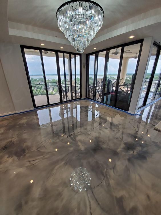 Modern room with glossy marble floor, crystal chandelier, and panoramic glass walls overlooking a scenic view