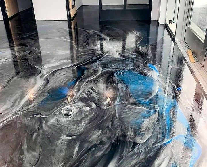 Shiny black and blue abstract floor art in a hallway with glass walls