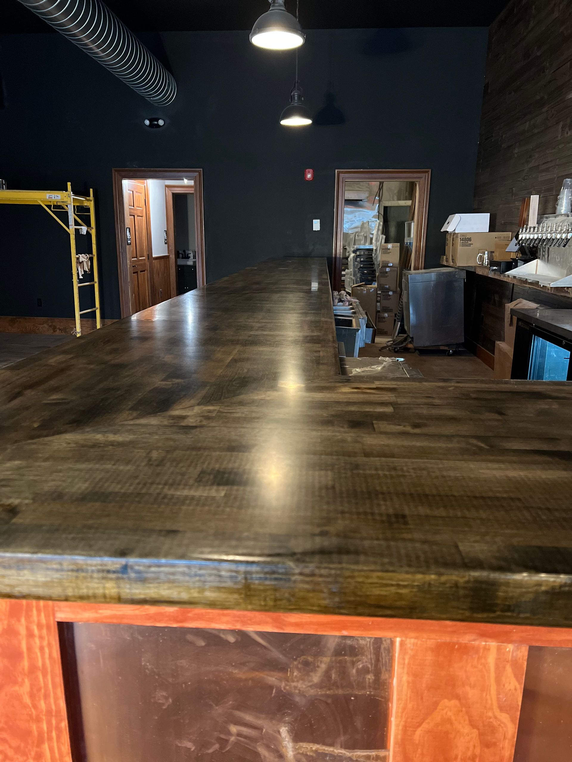 Empty industrial-style room with dark walls, wooden floor, and hanging lights