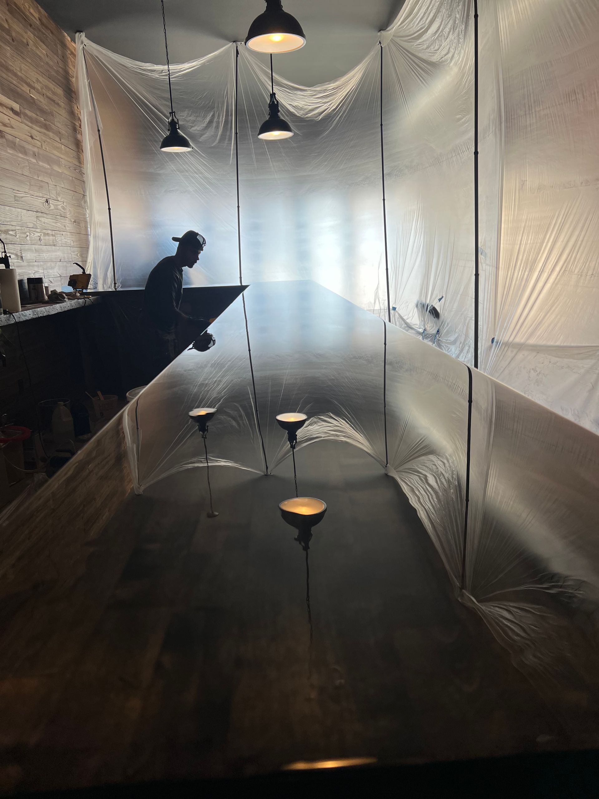Long, narrow room with reflective floor, white walls, hanging lights, and a dark bench along the left side.