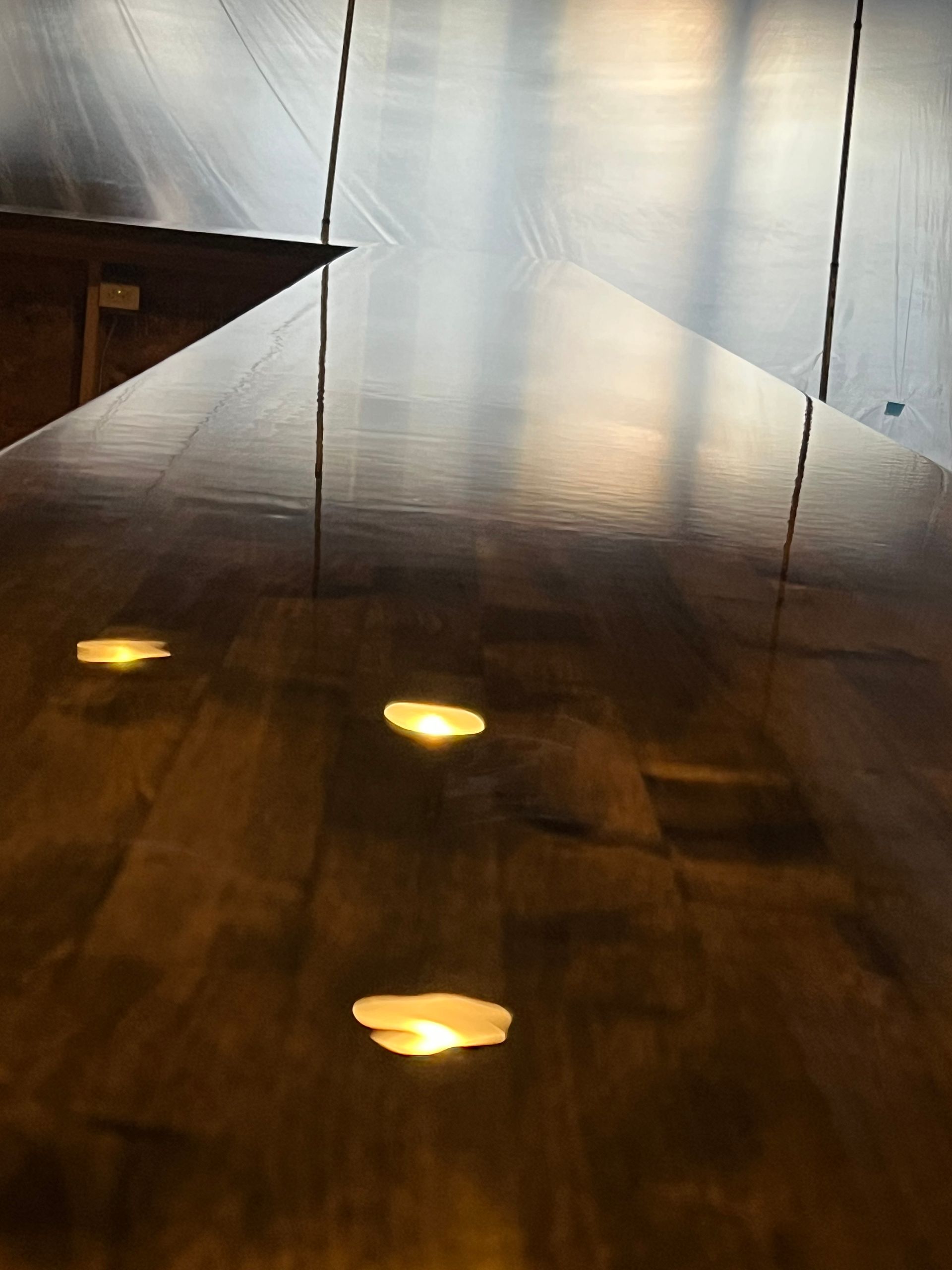 Dim hallway with glossy wood floor and three yellow reflections of lights on the ground.