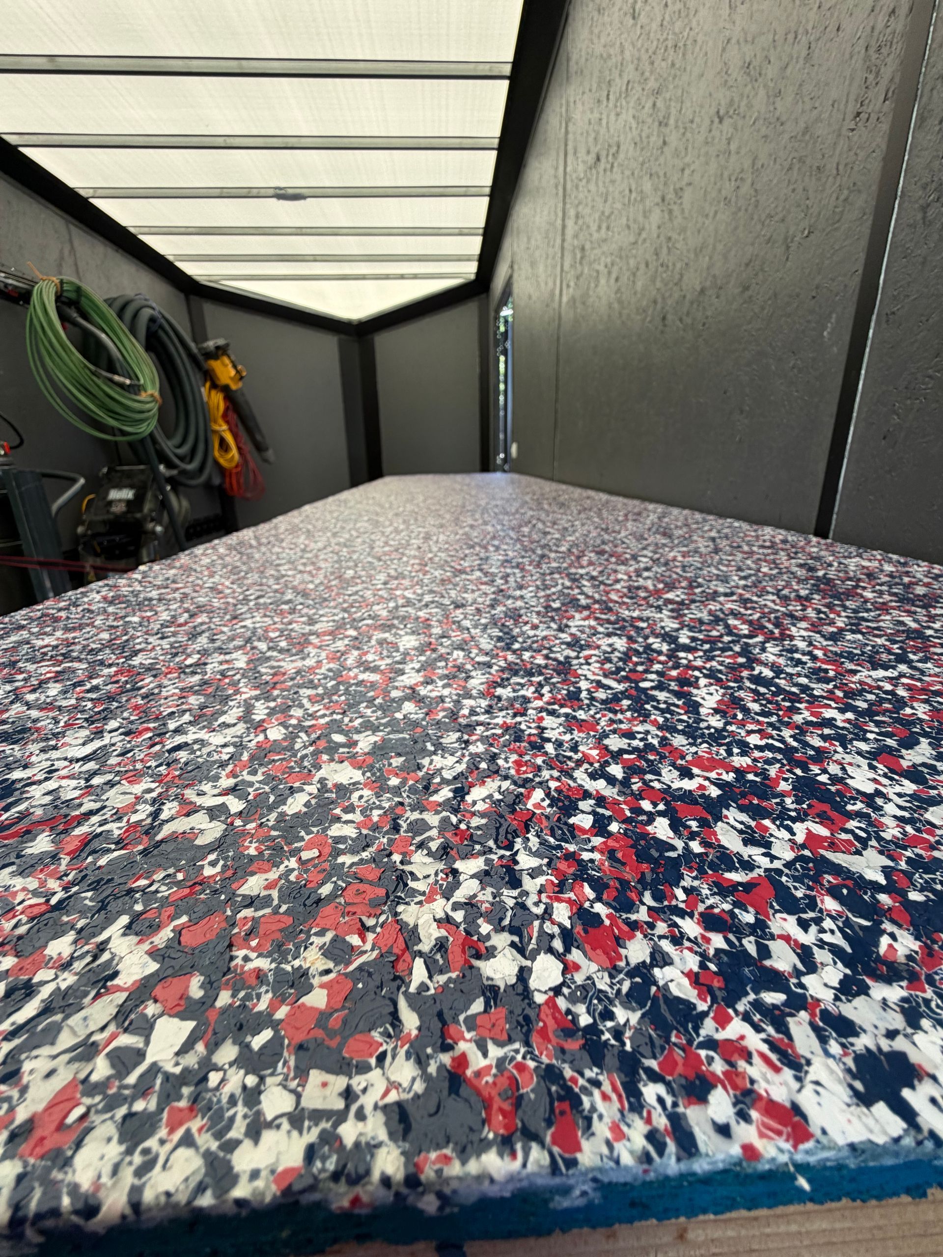 Close-up of a speckled red, white, and blue workbench inside a narrow storage trailer