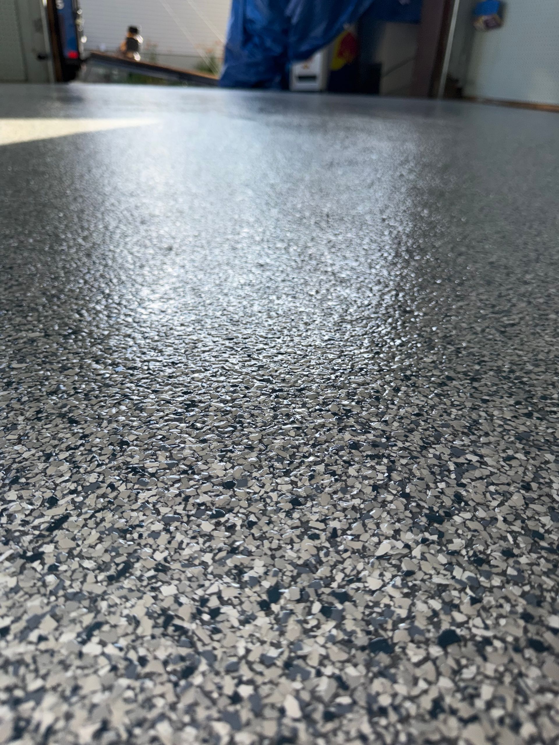 Close-up of a speckled gray floor with a glossy reflection in an indoor space