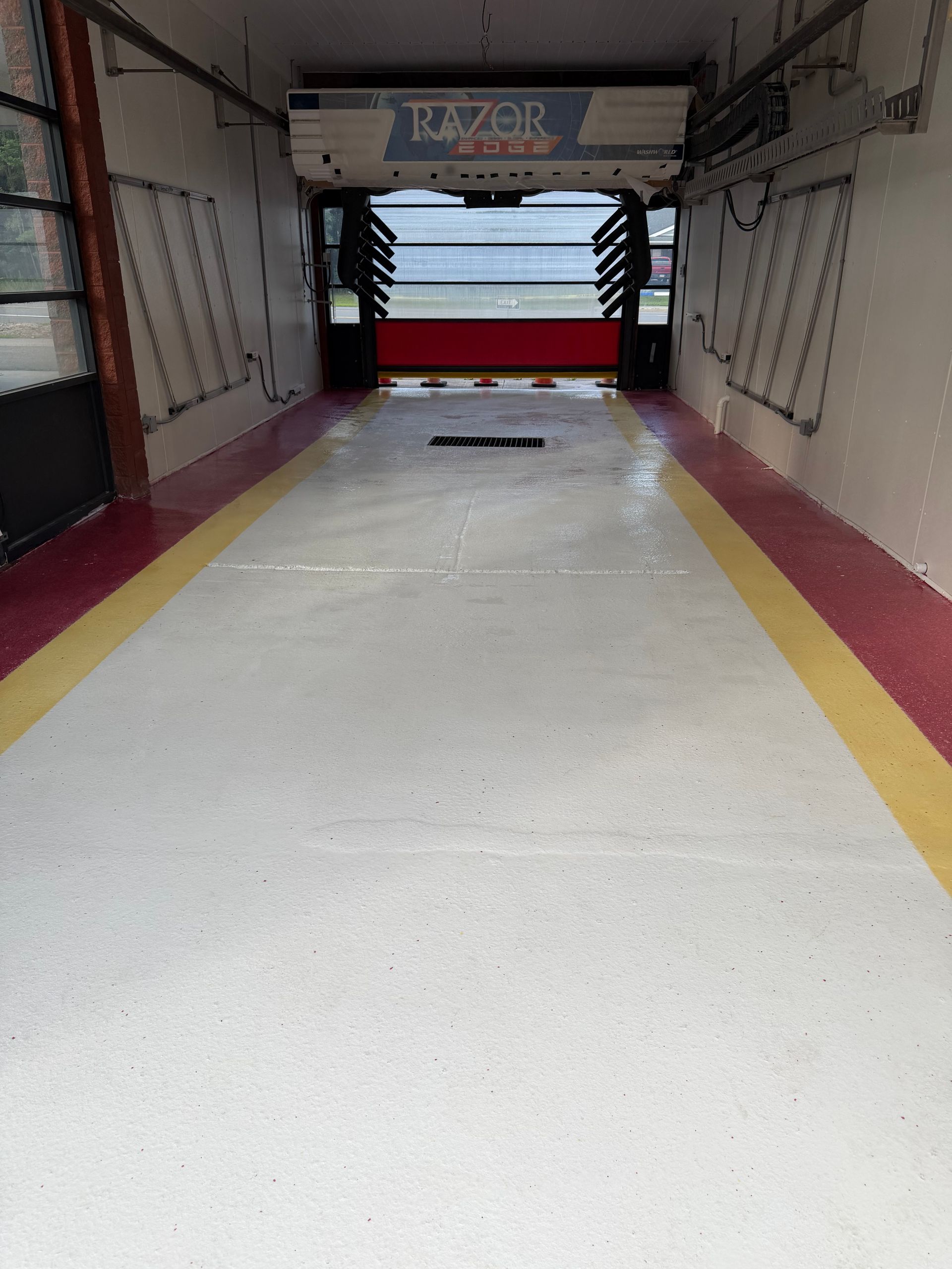 Empty indoor walkway with white floor, red side walls, and a red barrier at the end