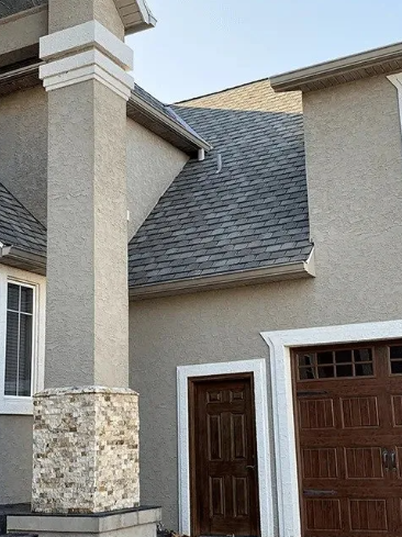 Exterior of a beige house with stone columns, brown garage doors, and a front entry door.