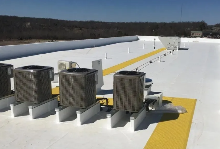 Three rooftop HVAC units on a white roof with yellow safety markings under a clear sky