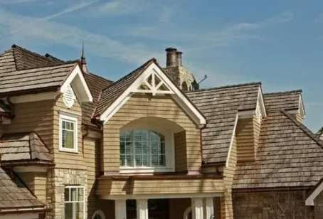 Large stone and shingle house exterior with multiple gables and a covered front balcony.