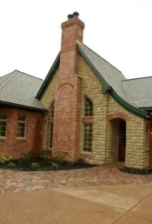 Brick-and-stone house exterior with a tall chimney and arched entryway