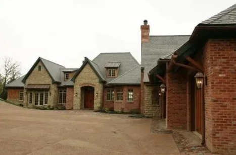 Brick and stone country house with gabled roofs and a large gravel courtyard