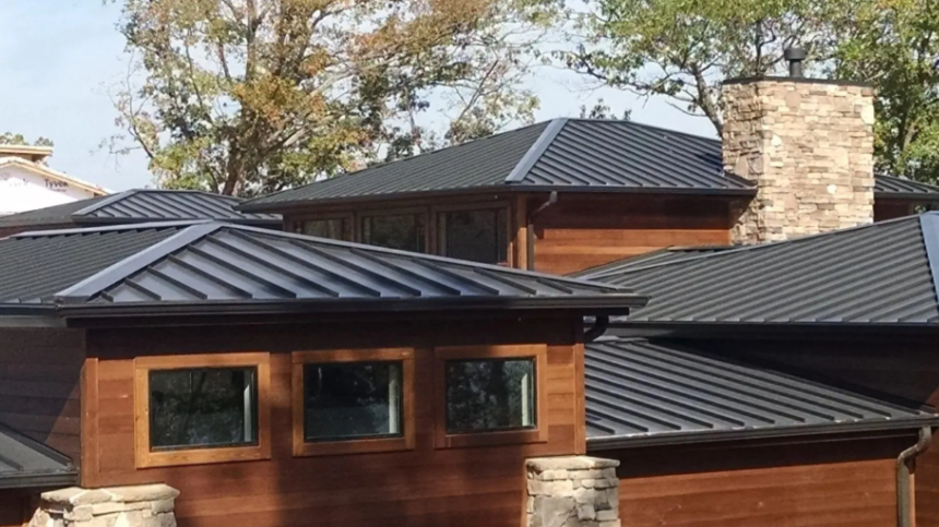 Modern house with dark metal roofs, wood siding, and stone chimneys among trees