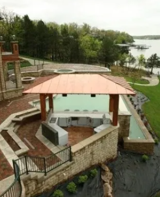 Riverside gazebo with a red roof beside stone terraces, trees, and water