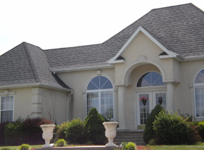 Suburban house with gray roof, arched windows, and front shrubs