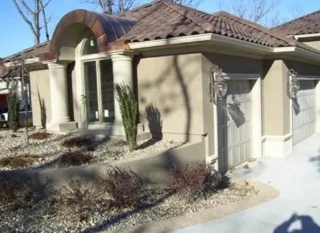 Single-story beige house with a curved front entry, brown roof, and snow-covered yard