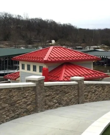 Red-roofed building behind a stone wall in a wooded area on an overcast day