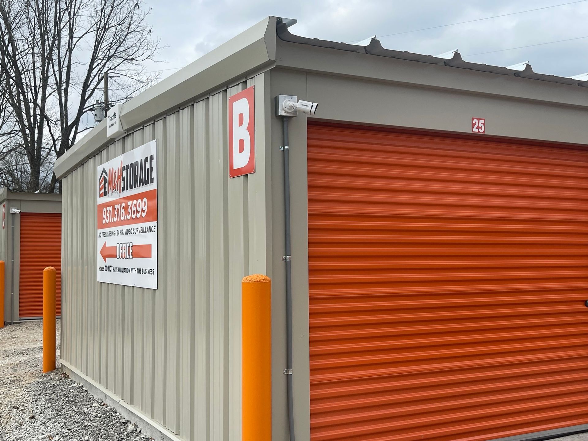 A storage unit with orange roller doors and a sign on the side.