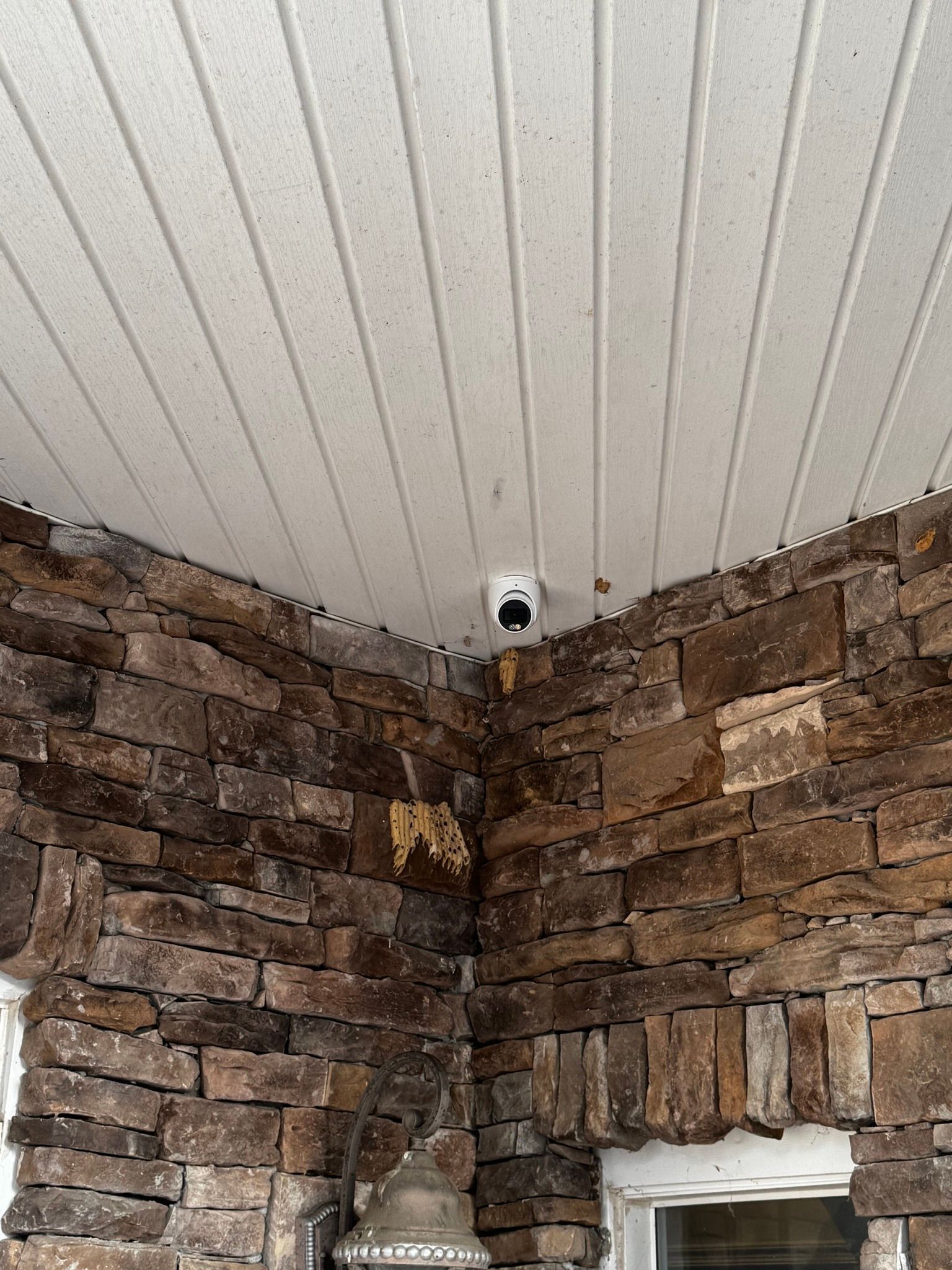 A camera is mounted on the ceiling of a stone wall.