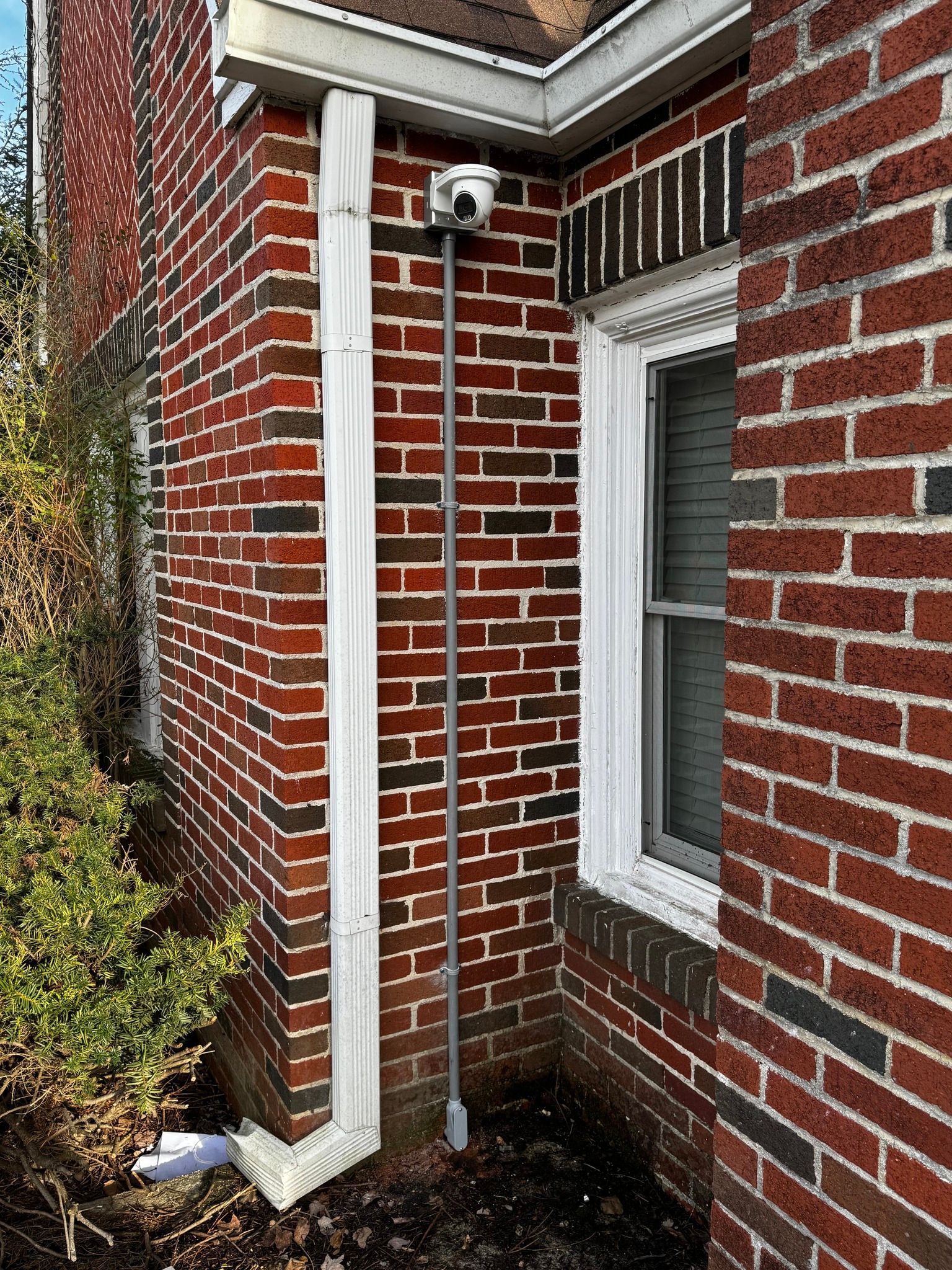 A brick building with a window and a drain pipe on the side.