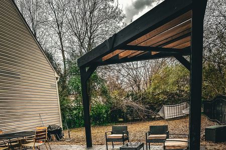 A patio with chairs and a table under a pergola.