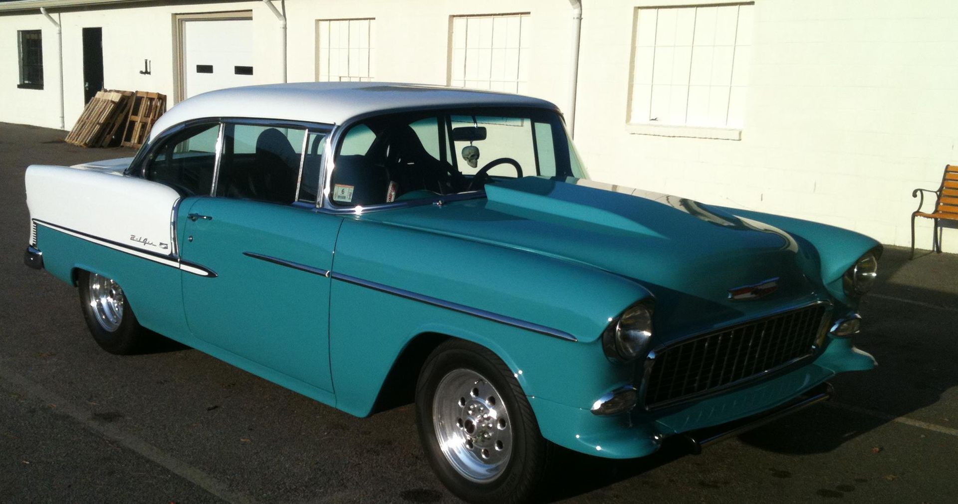 A blue and white car is parked in front of a building.