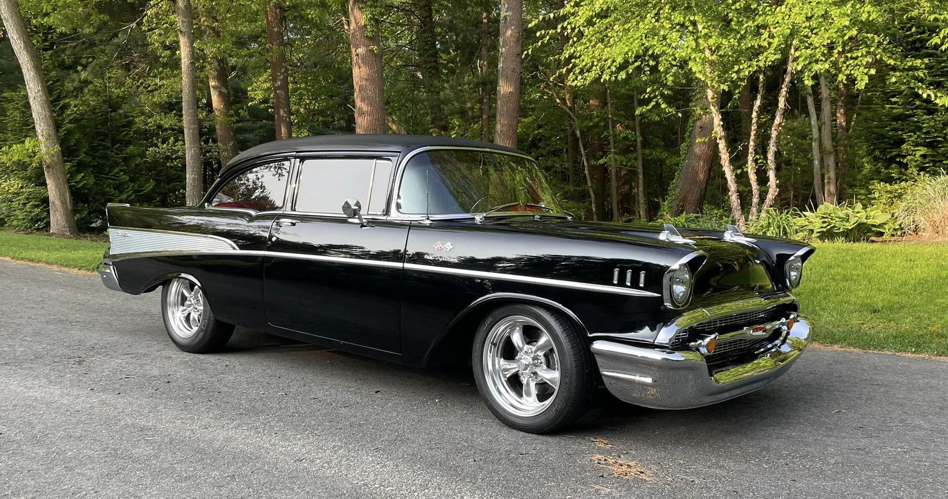 A black classic car is parked on the side of the road.