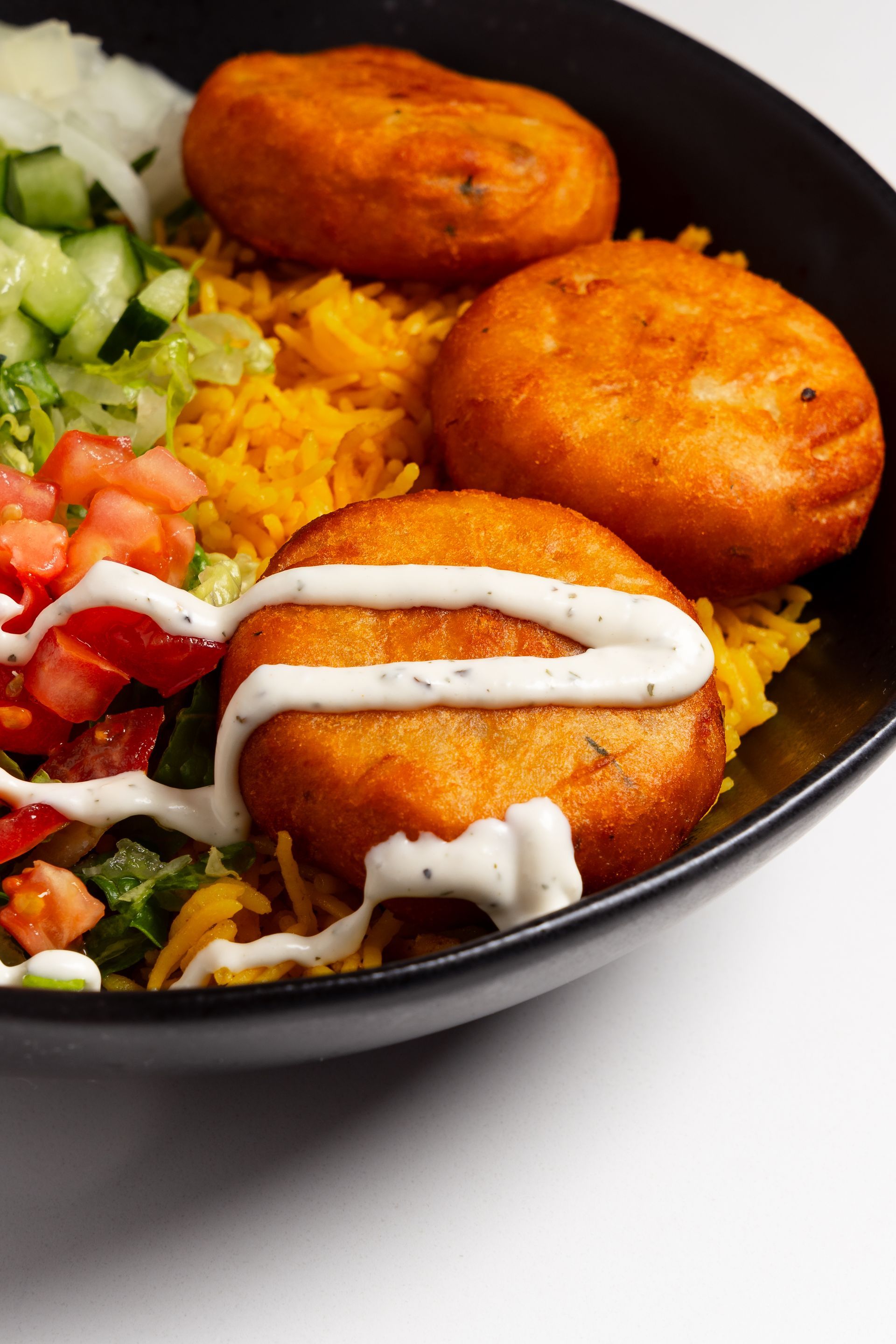 A close up of a fork holding a piece of food over a plate of food.