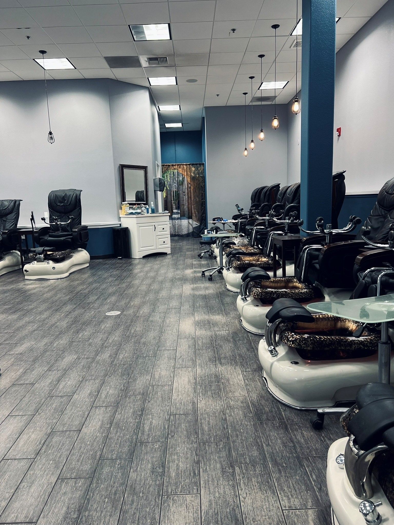 a nail salon with a lot of chairs and a mirror