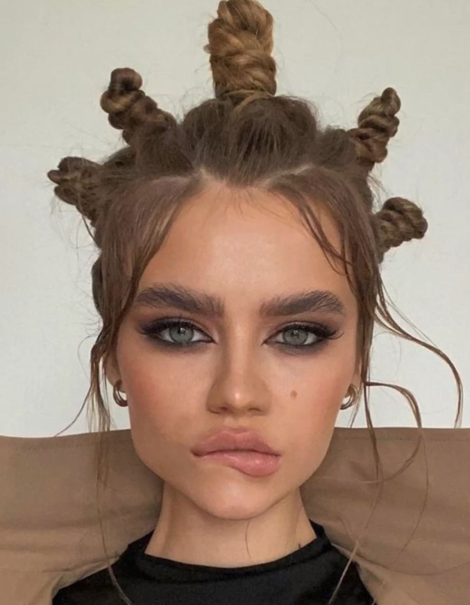 a woman with a bun in her hair looks at the camera