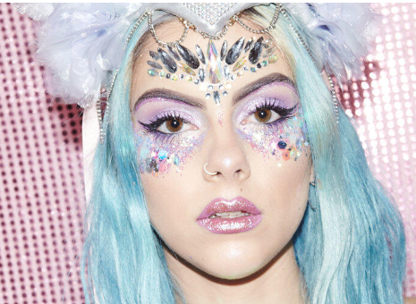 a woman with blue hair and rhinestones on her face .