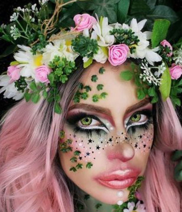 a woman with pink hair is wearing a flower crown on her head .