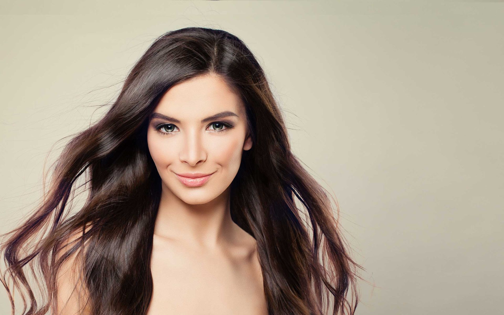 A woman with long hair is smiling and looking at the camera.
