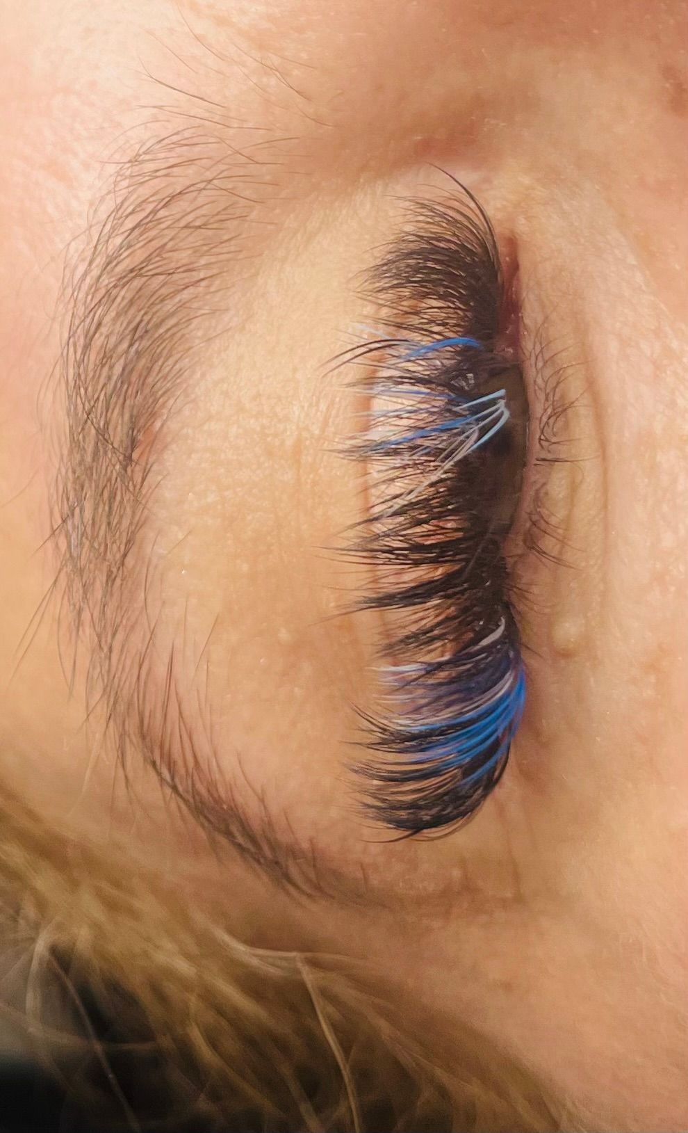 a close up of a woman 's eye with blue eyelashes .