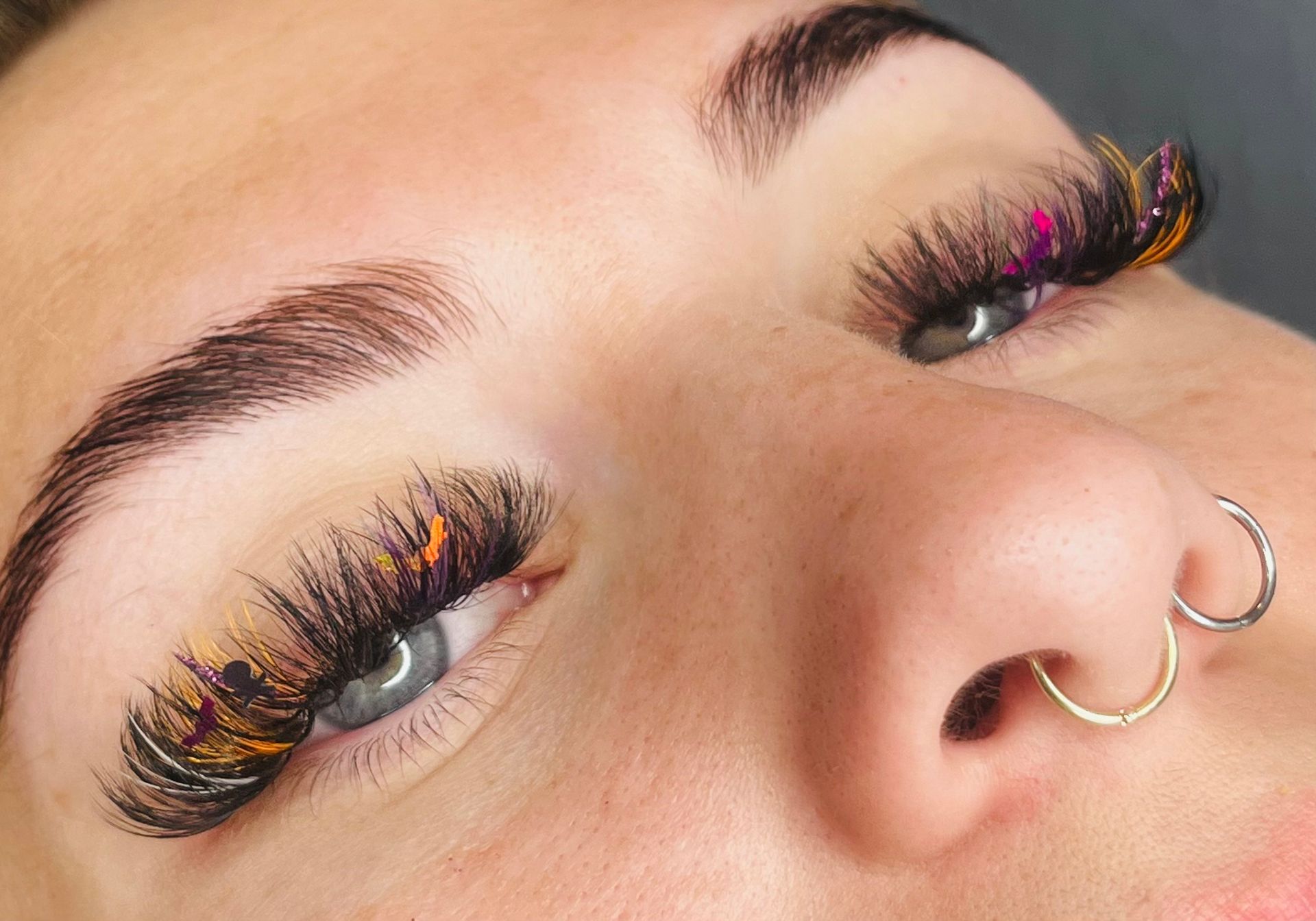 a close up of a woman 's face with long eyelashes and a nose ring .