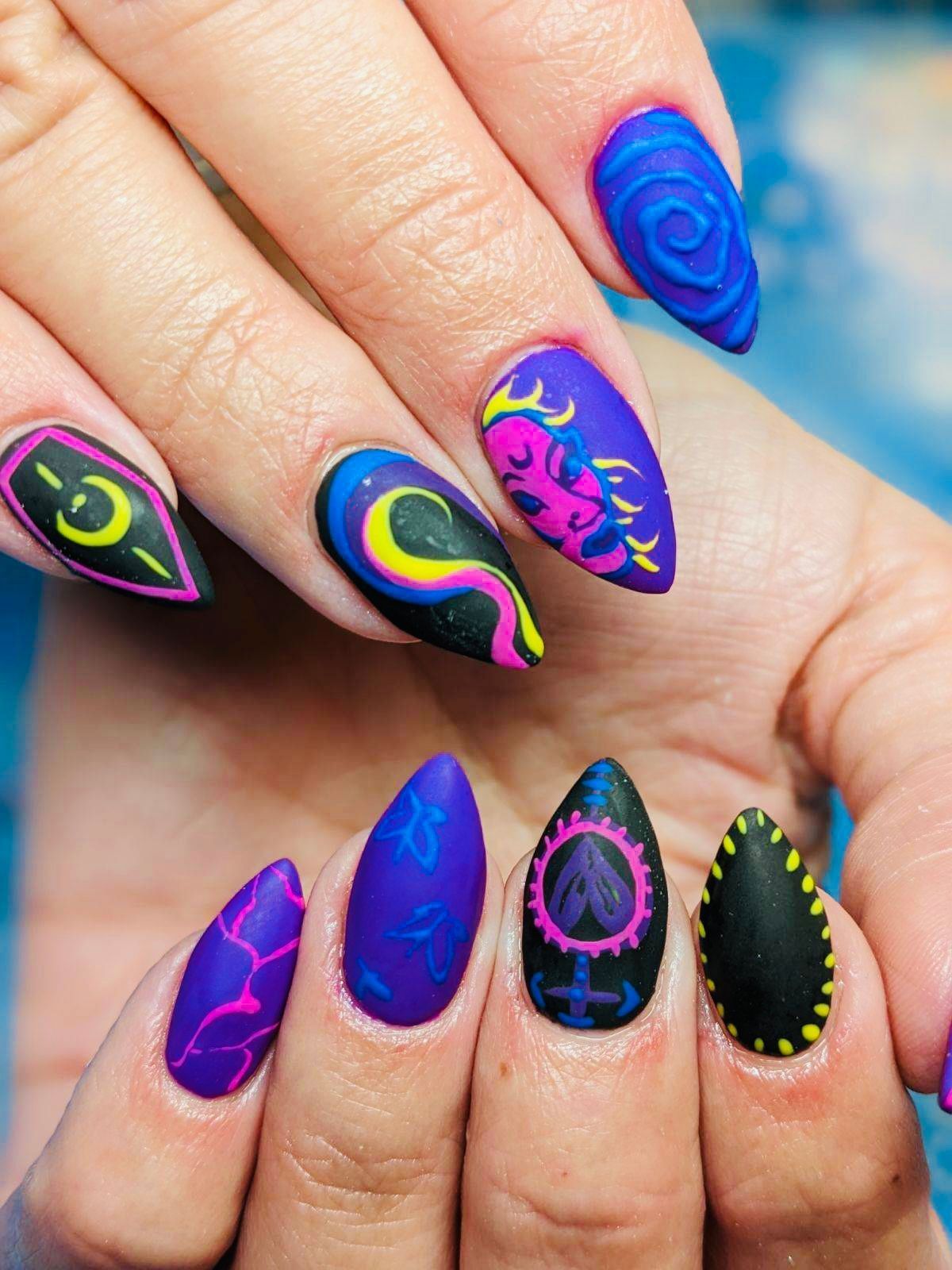 a close up of a woman 's nails with purple and black designs