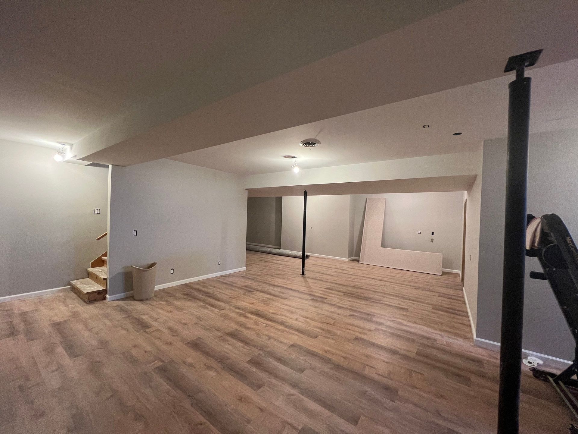 An empty basement with hardwood floors and stairs.