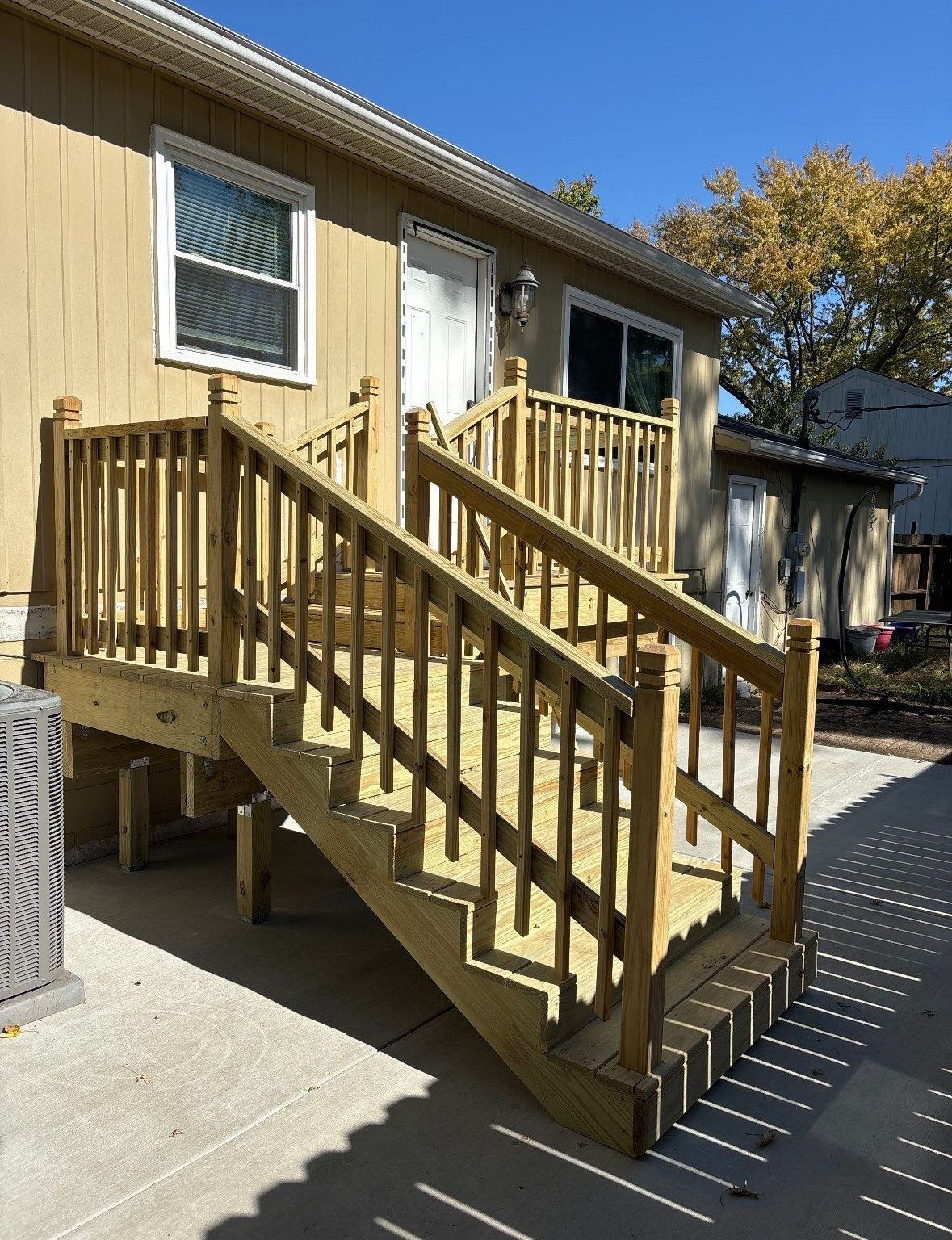 A mobile home with a wooden deck and stairs.