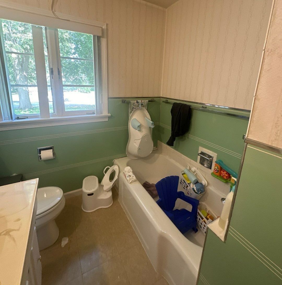 A bathroom with a tub, toilet, and window.