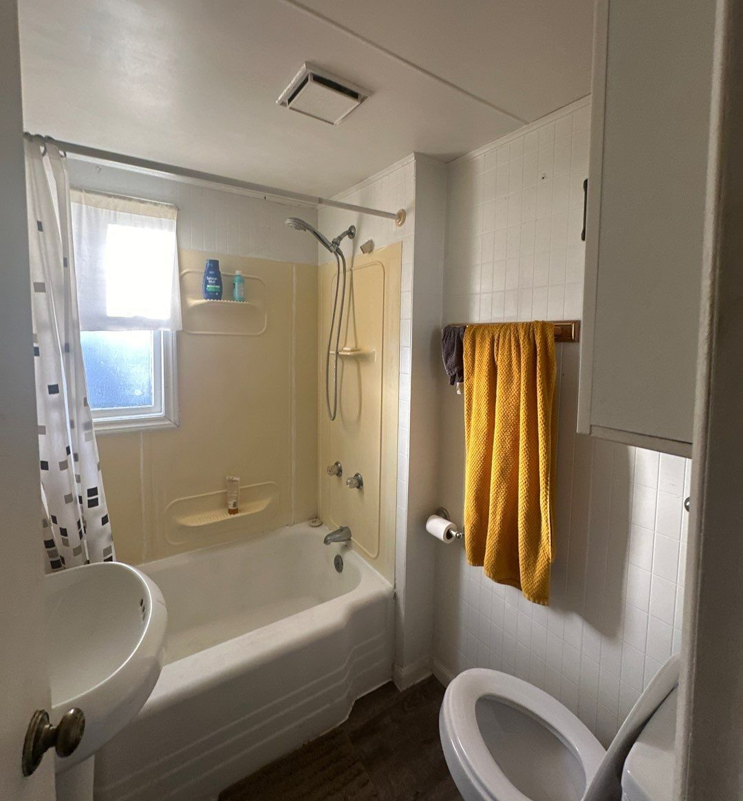 A bathroom with a toilet a sink and a bathtub.