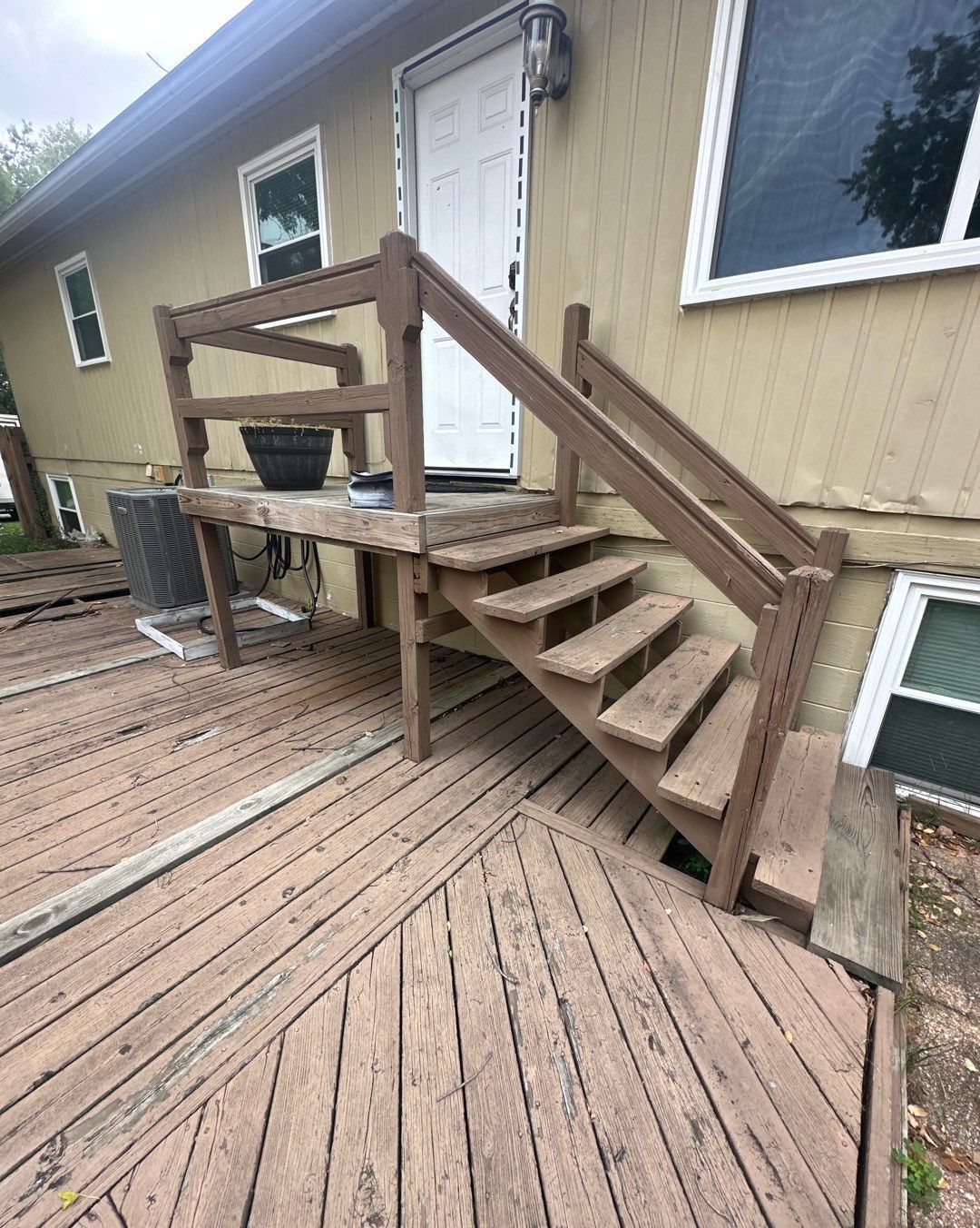 A wooden deck with stairs leading up to the front door of a house.