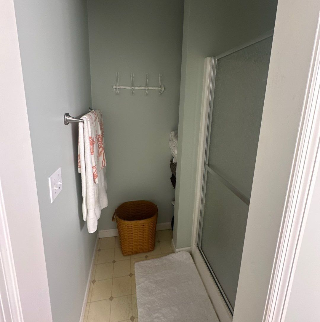 A bathroom with a walk-in shower and a basket on the floor.