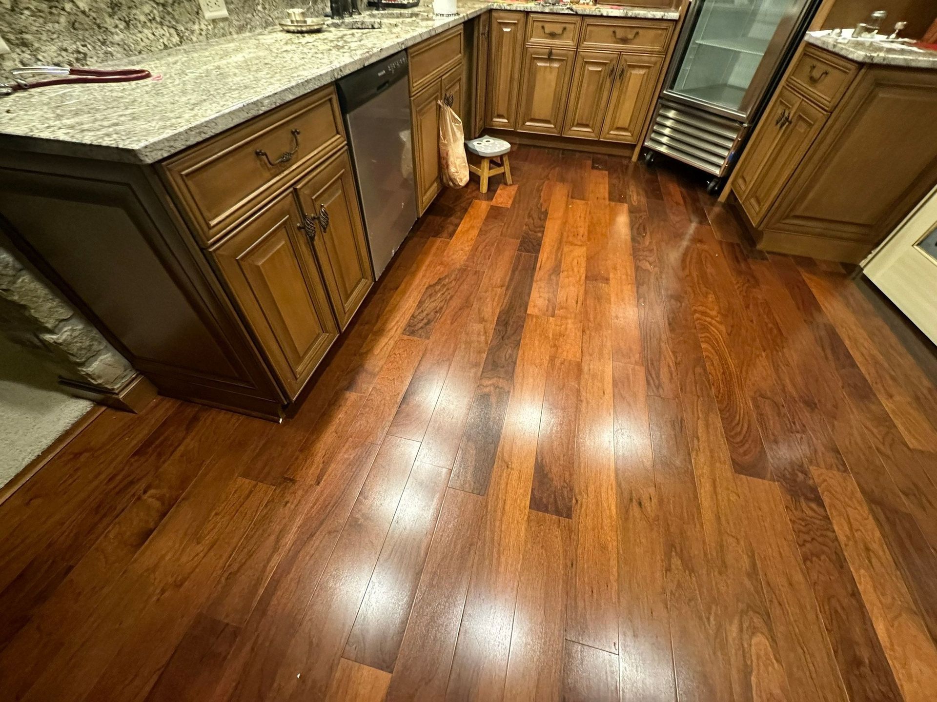 A kitchen with hardwood floors , granite counter tops , and wooden cabinets.