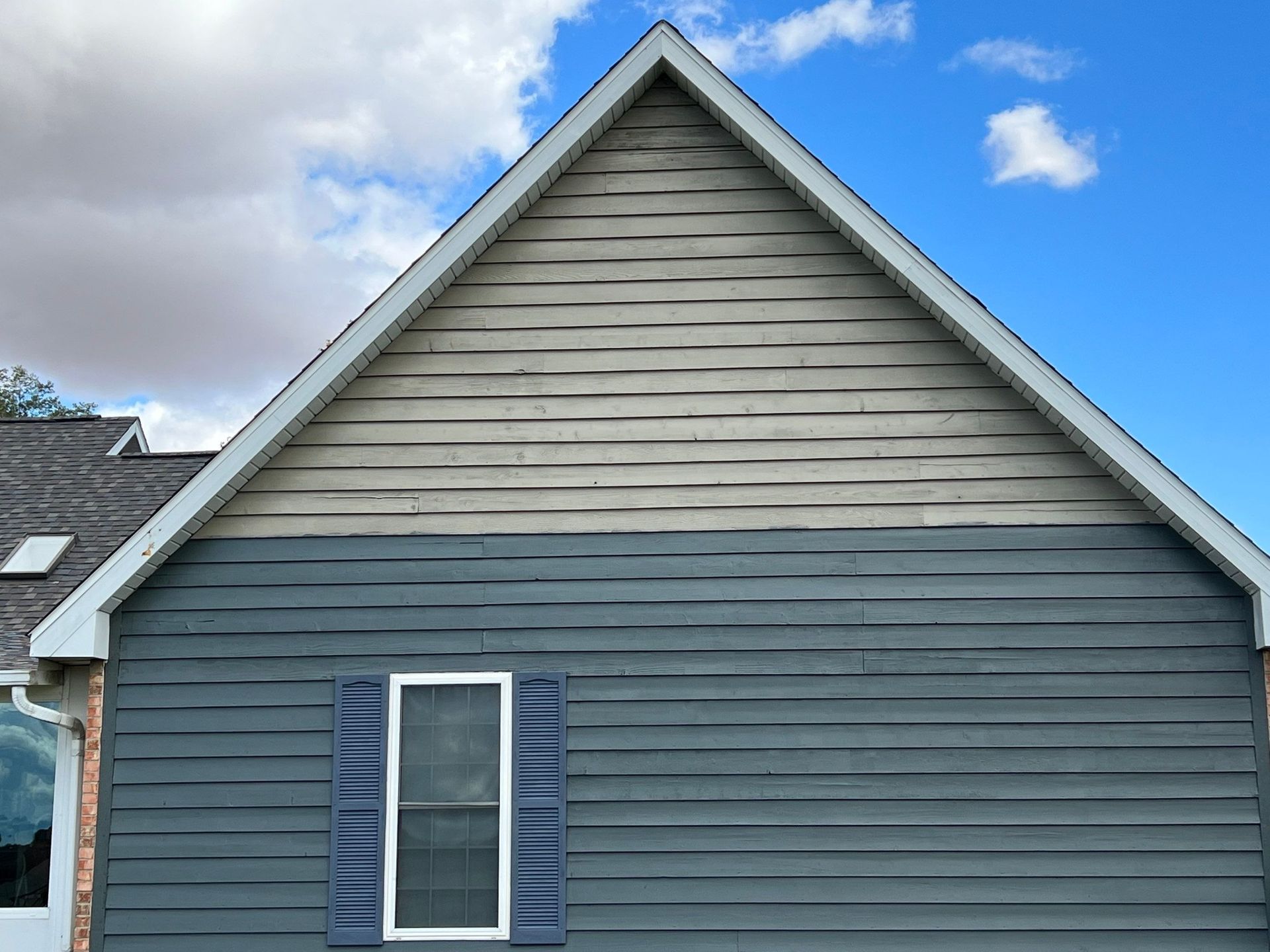 The side of a house with a window and a roof.