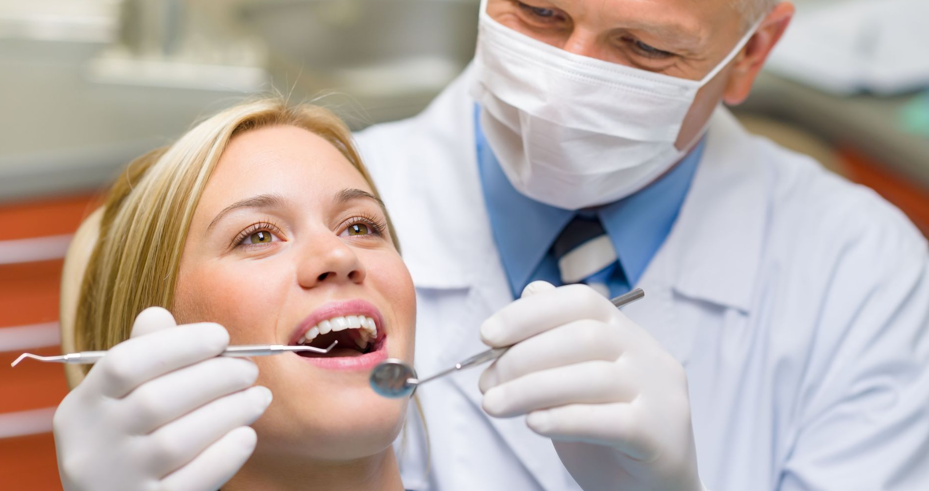 Dentist examining a patient's teeth with dental instruments in a clinic setting.