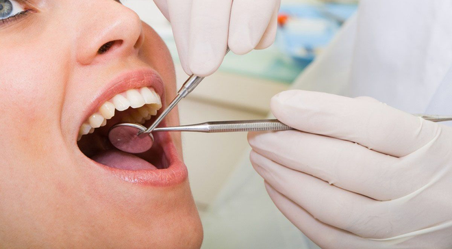 Dentist examining a patient's mouth with a mirror and probe.