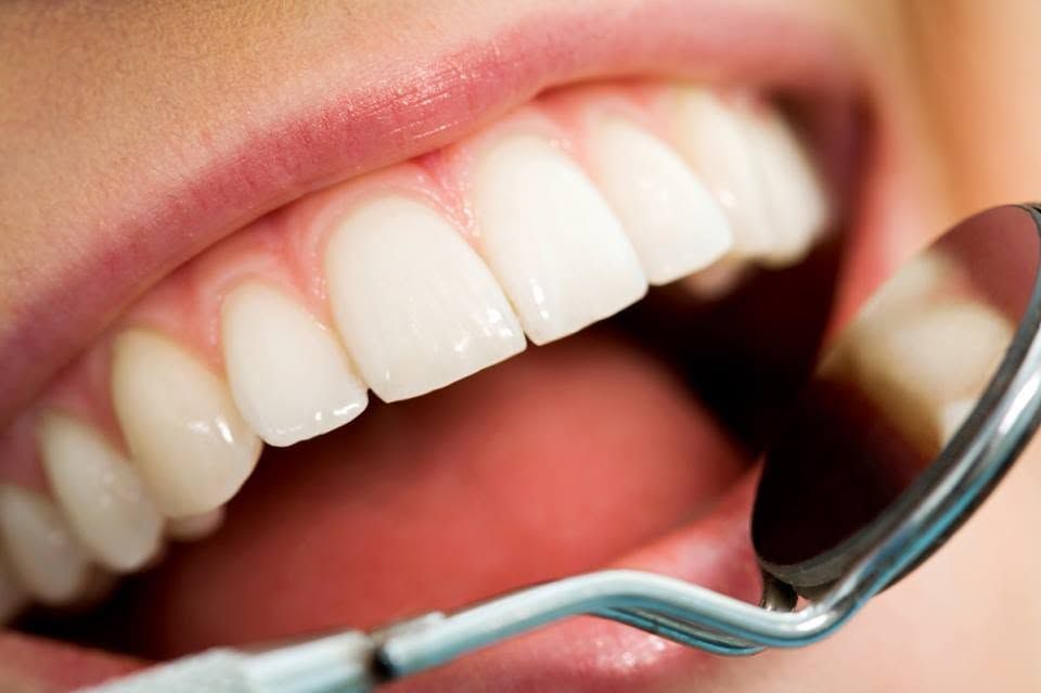 Close-up of teeth being examined with a dental mirror and tool