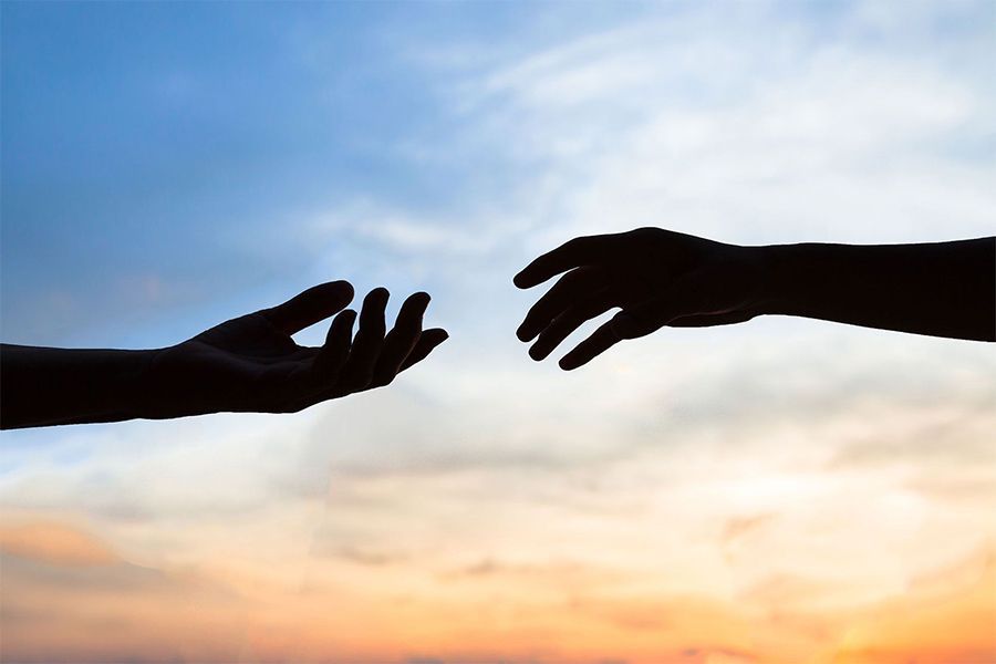 A silhouette of two hands reaching out towards each other
