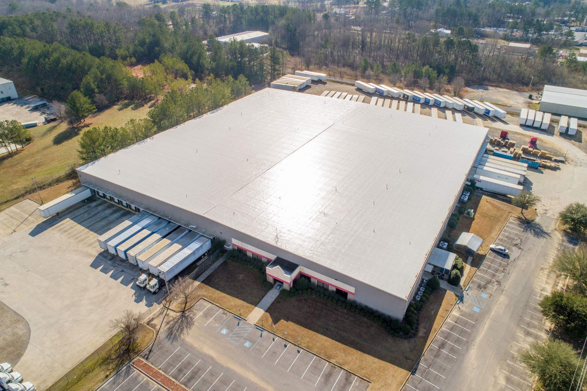 Large industrial warehouse with multiple loading docks, trucks, and parking area.