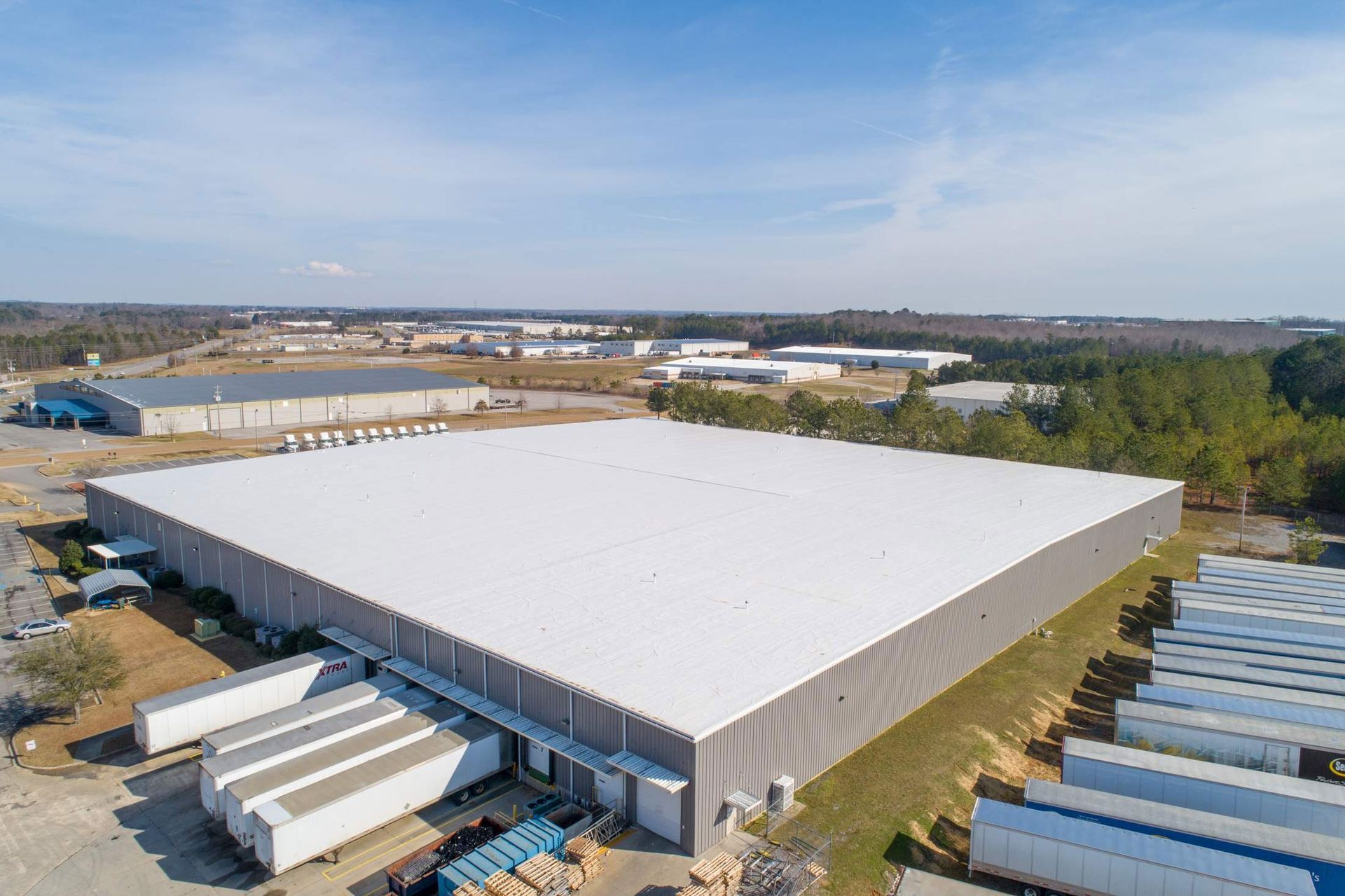 Aerial view of large industrial warehouse with trucks and loading docks.
