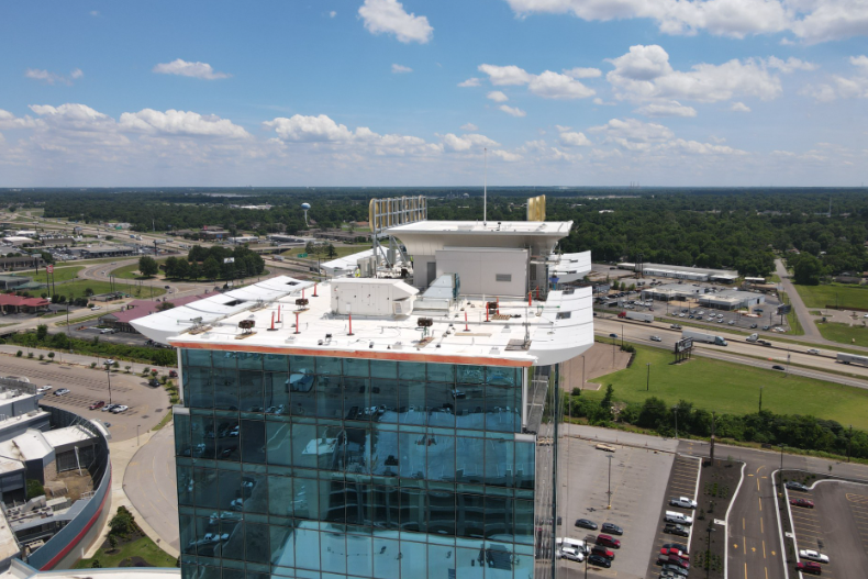 An aerial view of a tall building with a white roof
