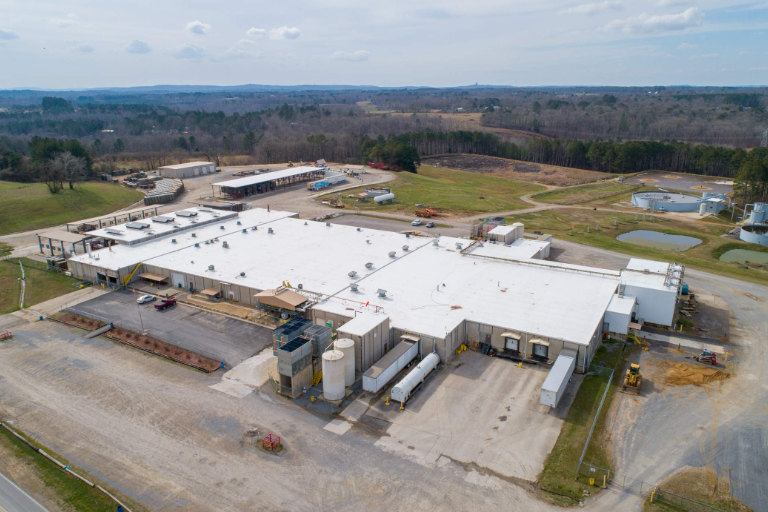 An aerial view of a large industrial building with a white roof.