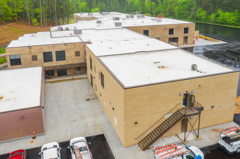 An aerial view of a large building with a white roof.